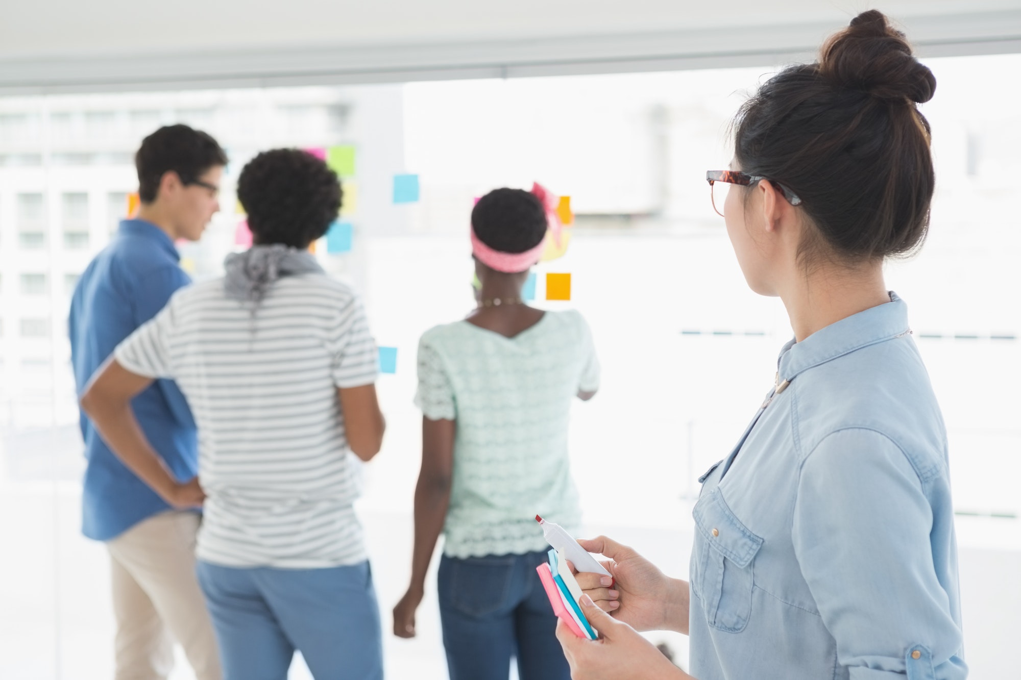 Young creative woman looking at team in creative office